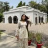 Model posing outdoors wearing an off-white pure Cameric cotton Farshi salwar suit set with a green dupatta.